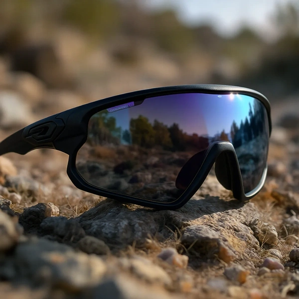 Sporta saulesbrilles ar atstarojošām lēcām novietotas uz akmeņainas zemes dabā